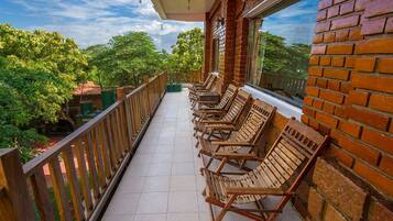 A balcony with wooden chairs and a view of greenery.