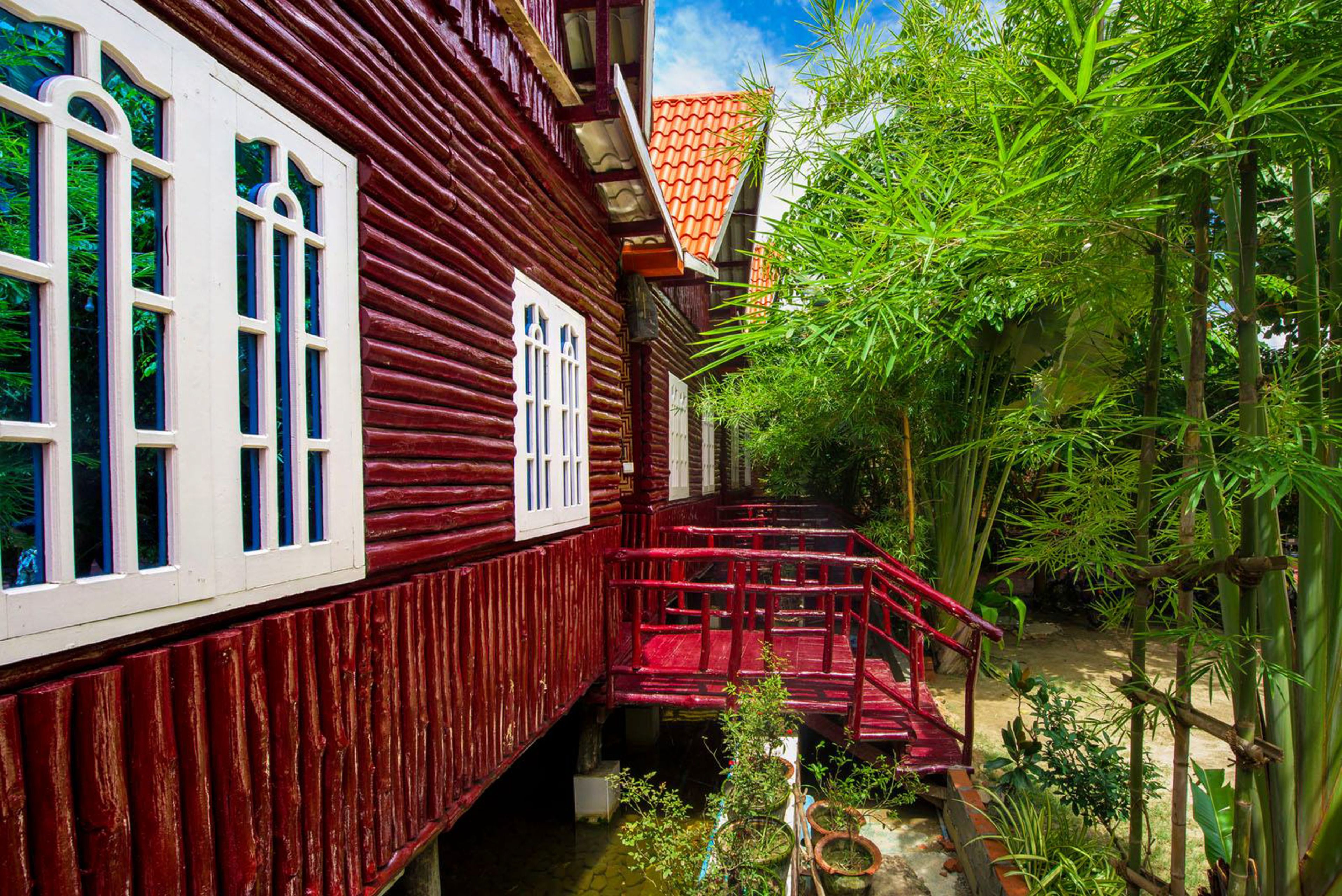 A traditional wooden house with a red exterior, white window frames, and a red staircase leading to a small porch.