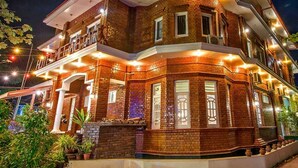 A multi-story building with a brick facade, multiple balconies, and outdoor lighting. - Hotel Mega Star (Mandalay)