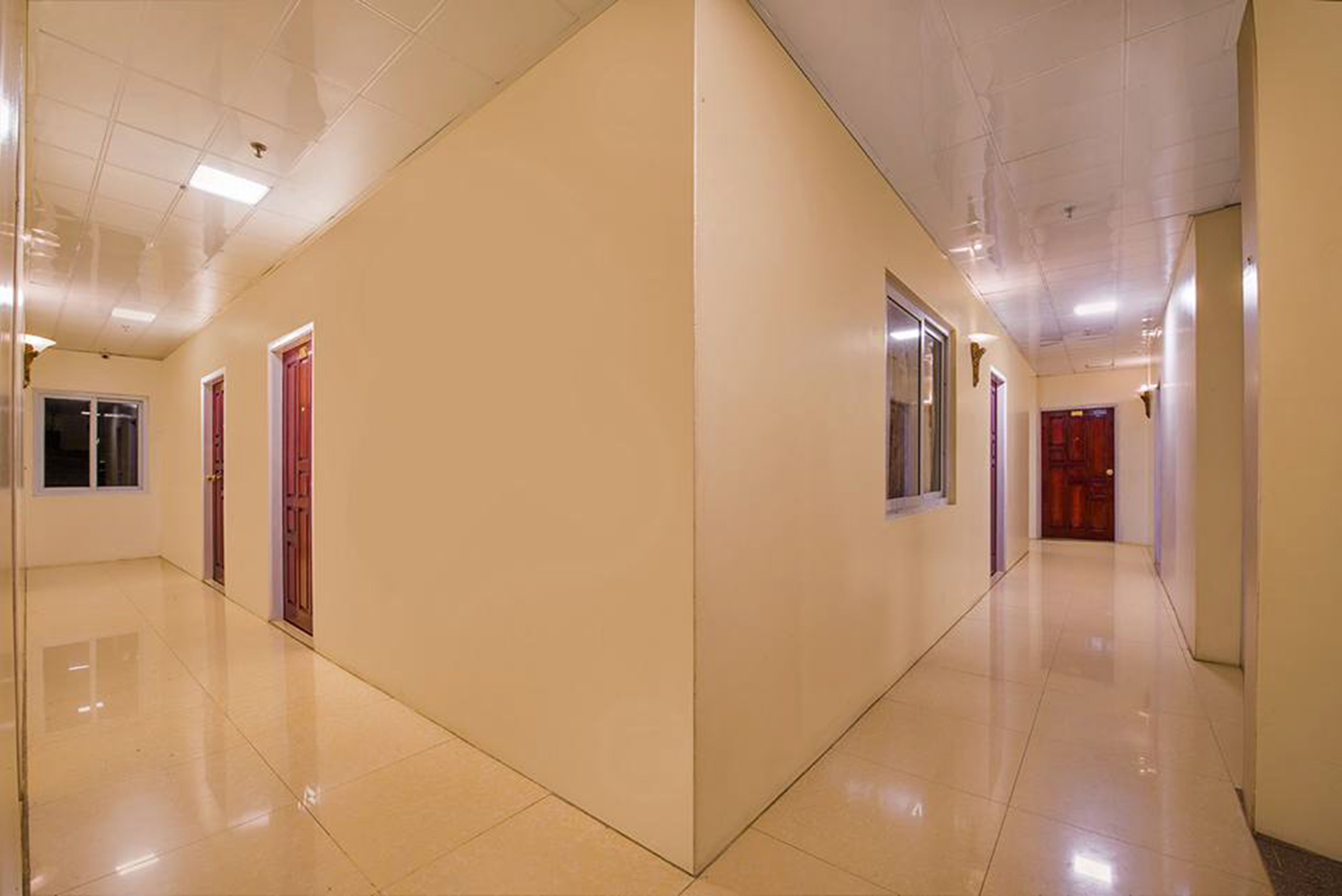 A corridor with beige walls and a shiny tiled floor.