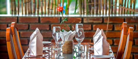 A dining table set with four wine glasses, two folded napkins, and a small woven basket.