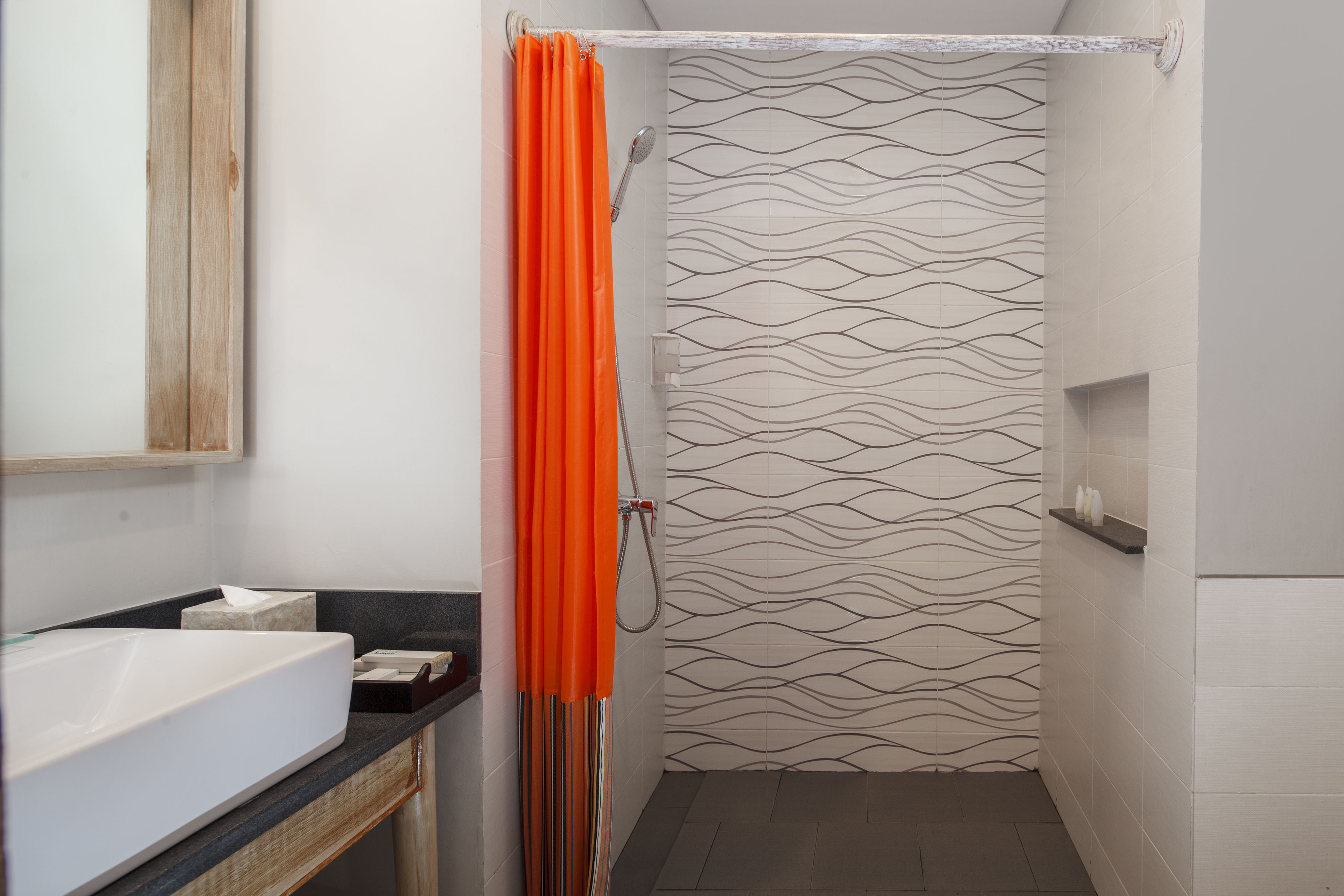 A bathroom with a white sink, a mirror, and a shower with a patterned wall.
