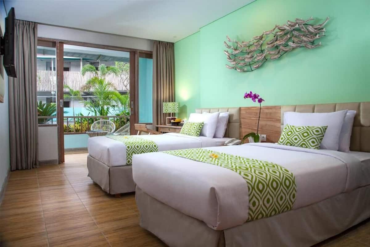 Ein Hotelzimmer mit zwei Betten, einem großen Fenster, Fisch-Wandbild und Blick ins Freie.