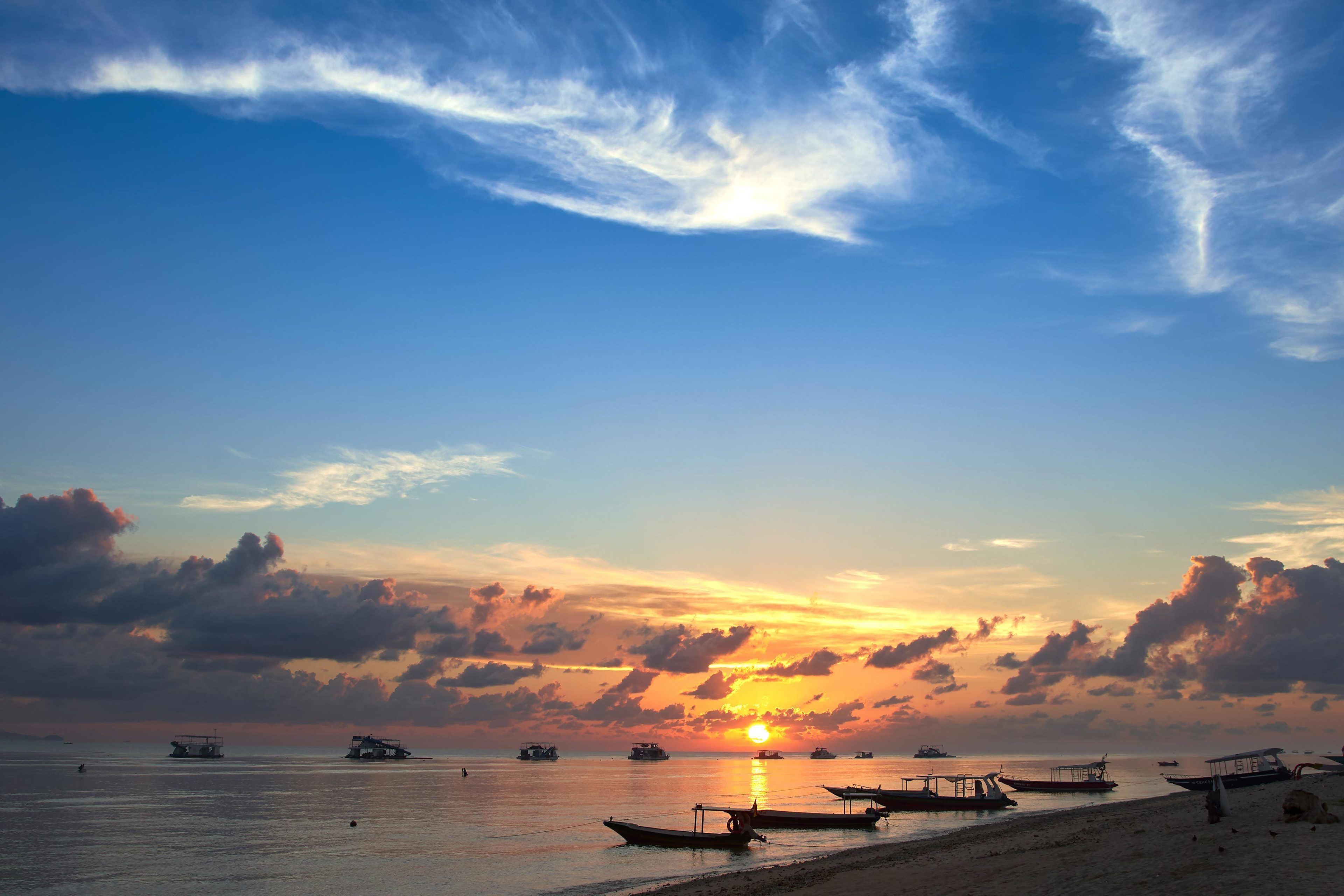 A beach with boats and a sunset.