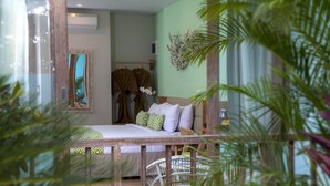 A room with a bed, a mirror, a wall-mounted air conditioner, and a decorative plant. - Mahagiri Resort Nusa Lembongan (Lembongan Island)