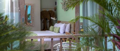 A room with a bed, a mirror, a wall-mounted air conditioner, and a decorative plant.
