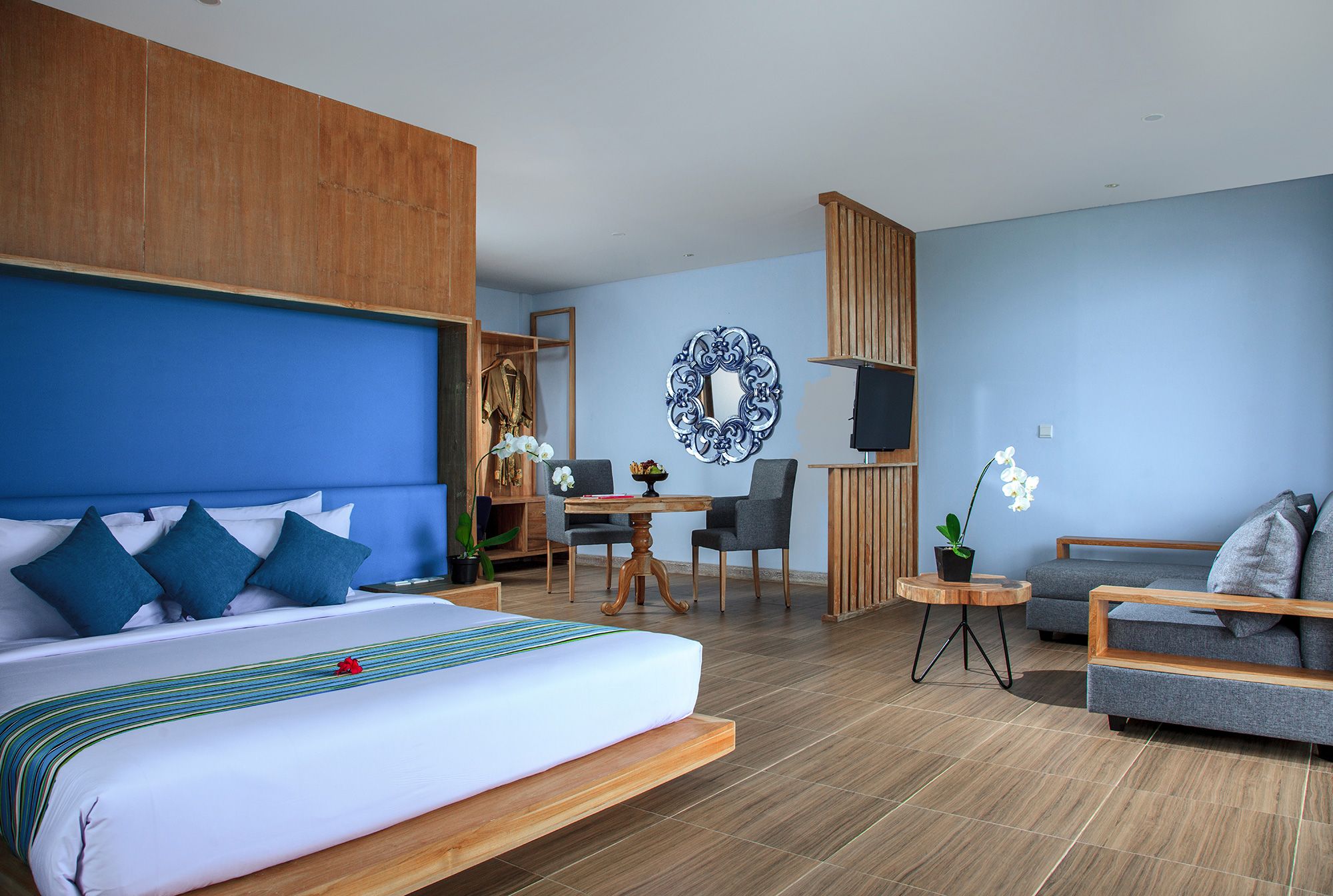 A hotel room with a large bed, a desk, a chair, a sofa, and a TV.