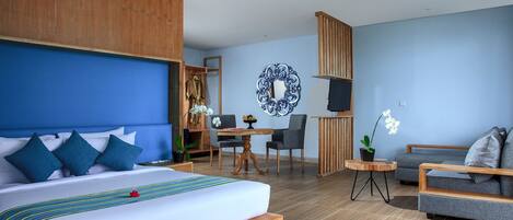 A hotel room with a large bed, a desk, a chair, a sofa, and a TV.