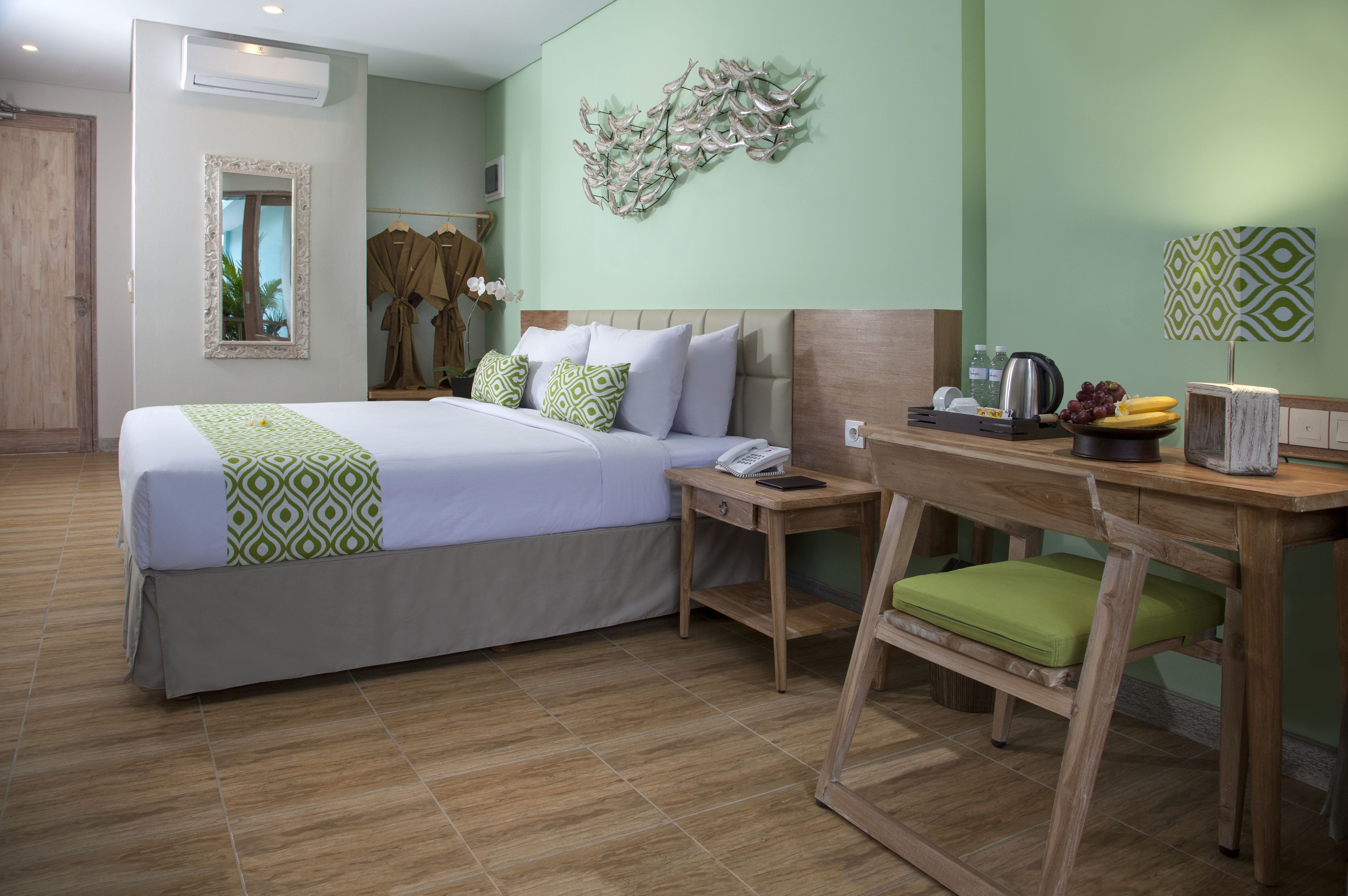 Una habitación de hotel con una cama grande, un escritorio de madera, una silla, un espejo y una obra de arte en la pared.