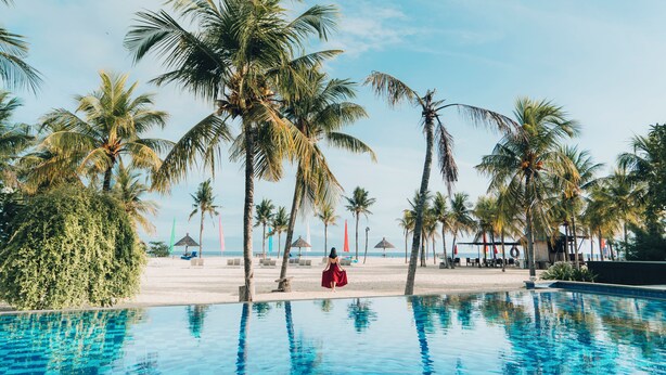 A pool area with palm trees and a beach in the background. - Mahagiri Resort Nusa Lembongan (Lembongan Island)
