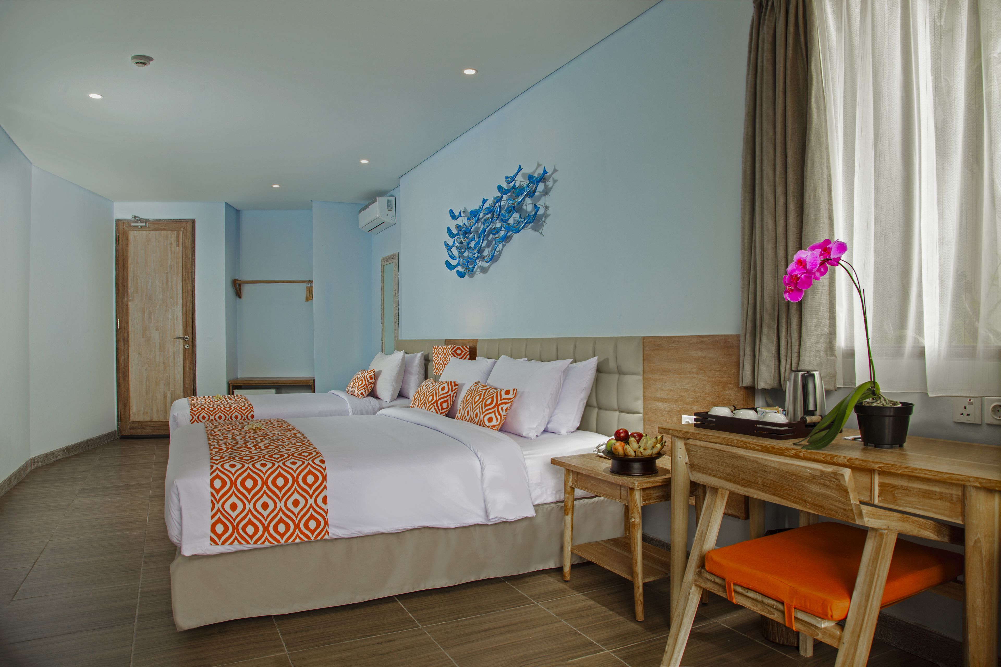 Une chambre d’hôtel équipée d’un lit, d’un bureau, d’une chaise, d’une plante en pot et d’un climatiseur fixé au mur.