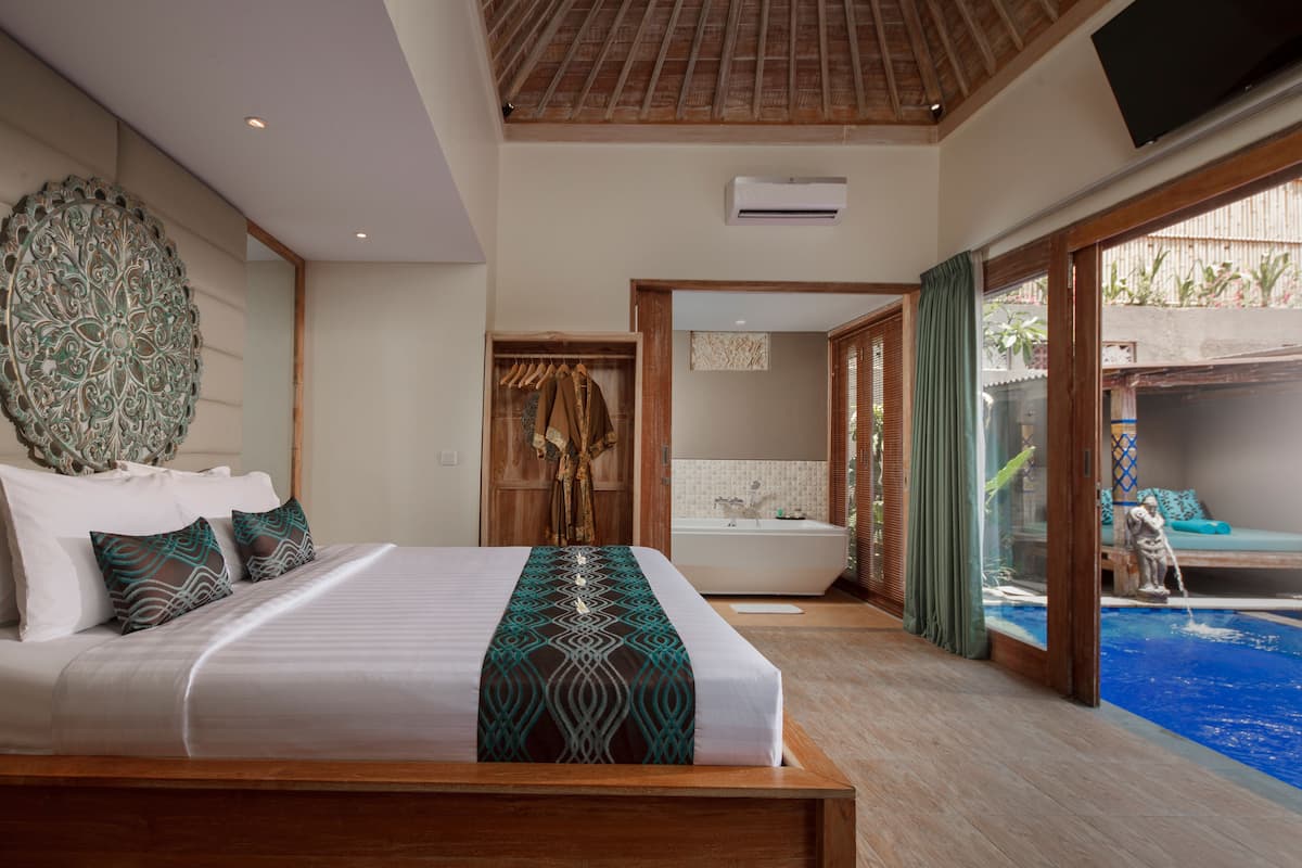 Ein Schlafzimmer mit einem großen Bett, ein Badezimmer mit einer Badewanne und Blick auf einen Swimmingpool.