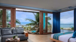 A modern hotel room with a balcony, a sofa, a bed, and a view of the ocean. - Mahagiri Resort Nusa Lembongan (Lembongan Island)