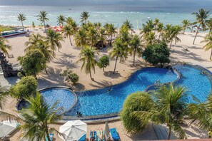 A pool area with a curved design, surrounded by palm trees and beach chairs. - Mahagiri Resort Nusa Lembongan (Lembongan Island)