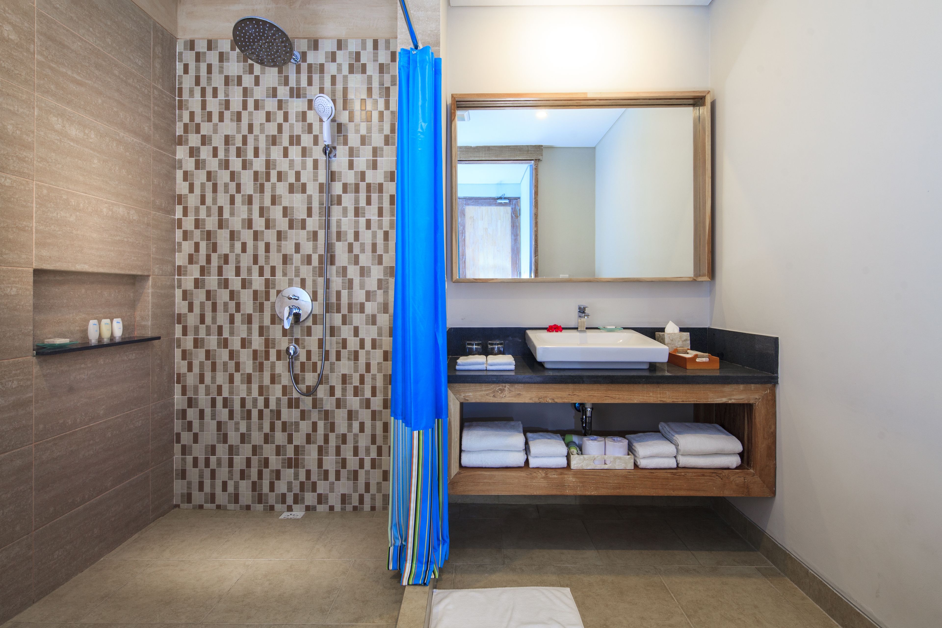 A modern bathroom with a checkered shower wall, a large mirror, a sink with a wooden vanity, and neatly folded towels.