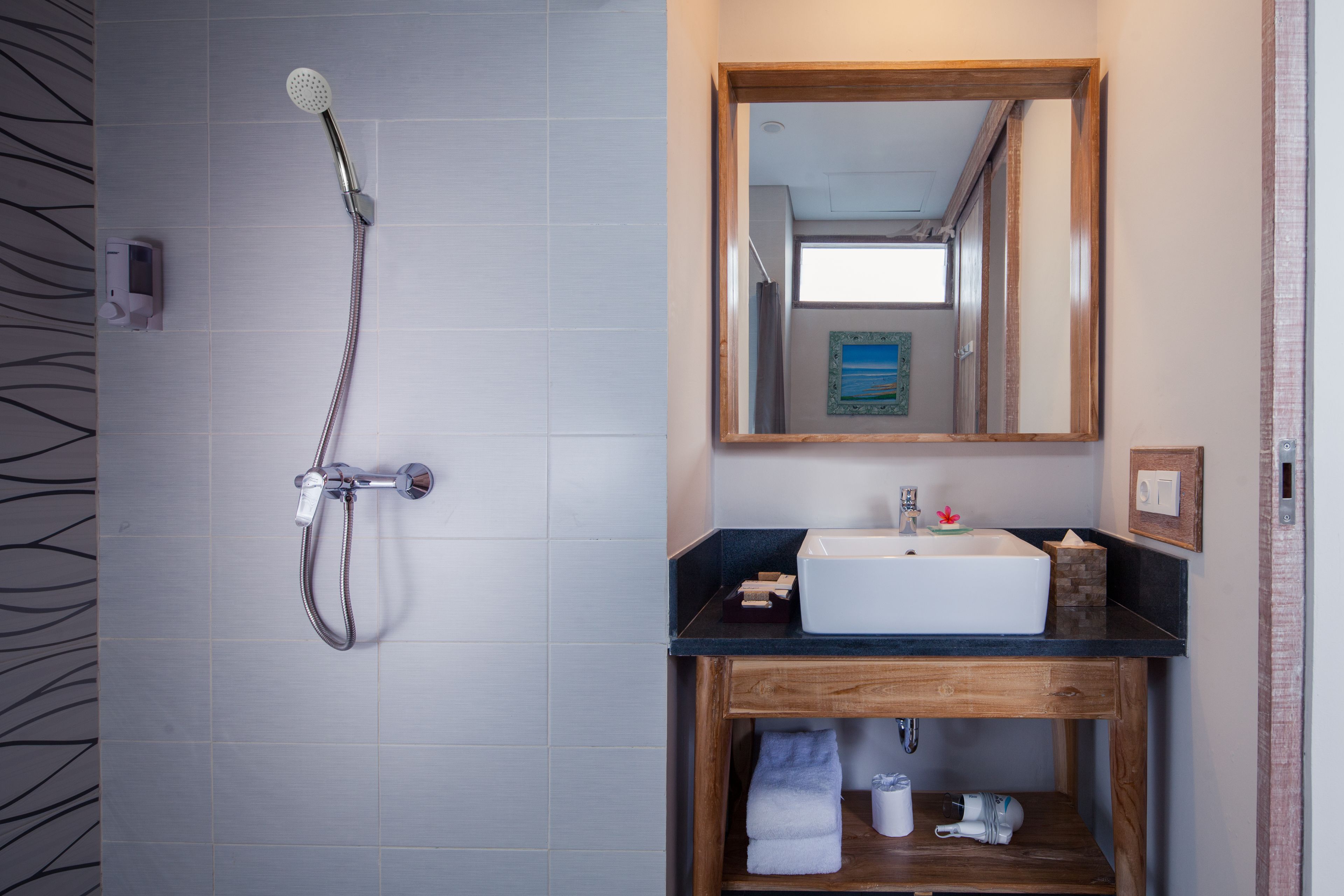 A bathroom with a shower, sink, and wooden vanity.