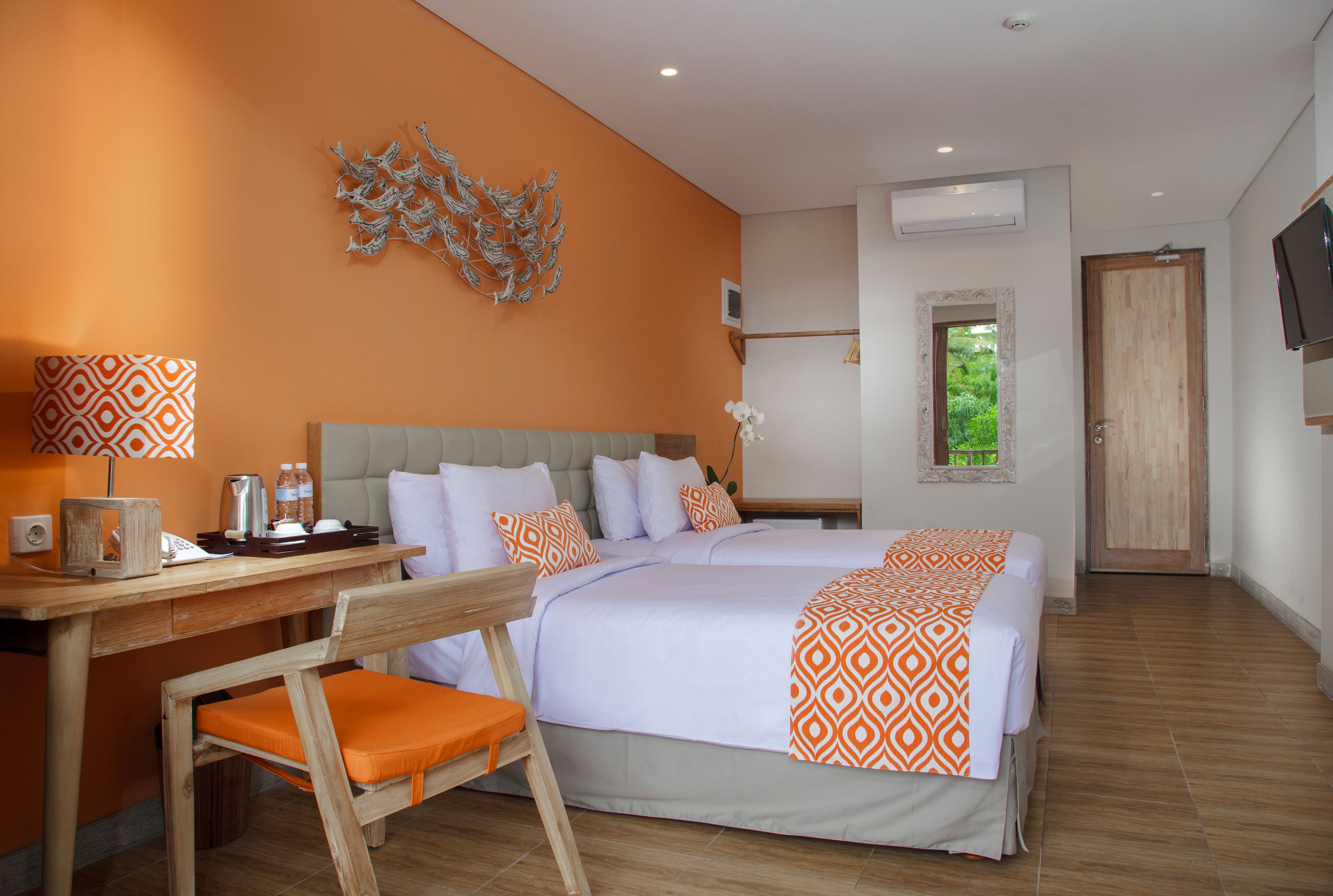 A hotel room with a bed, desk, chair, and a decorative wall piece.