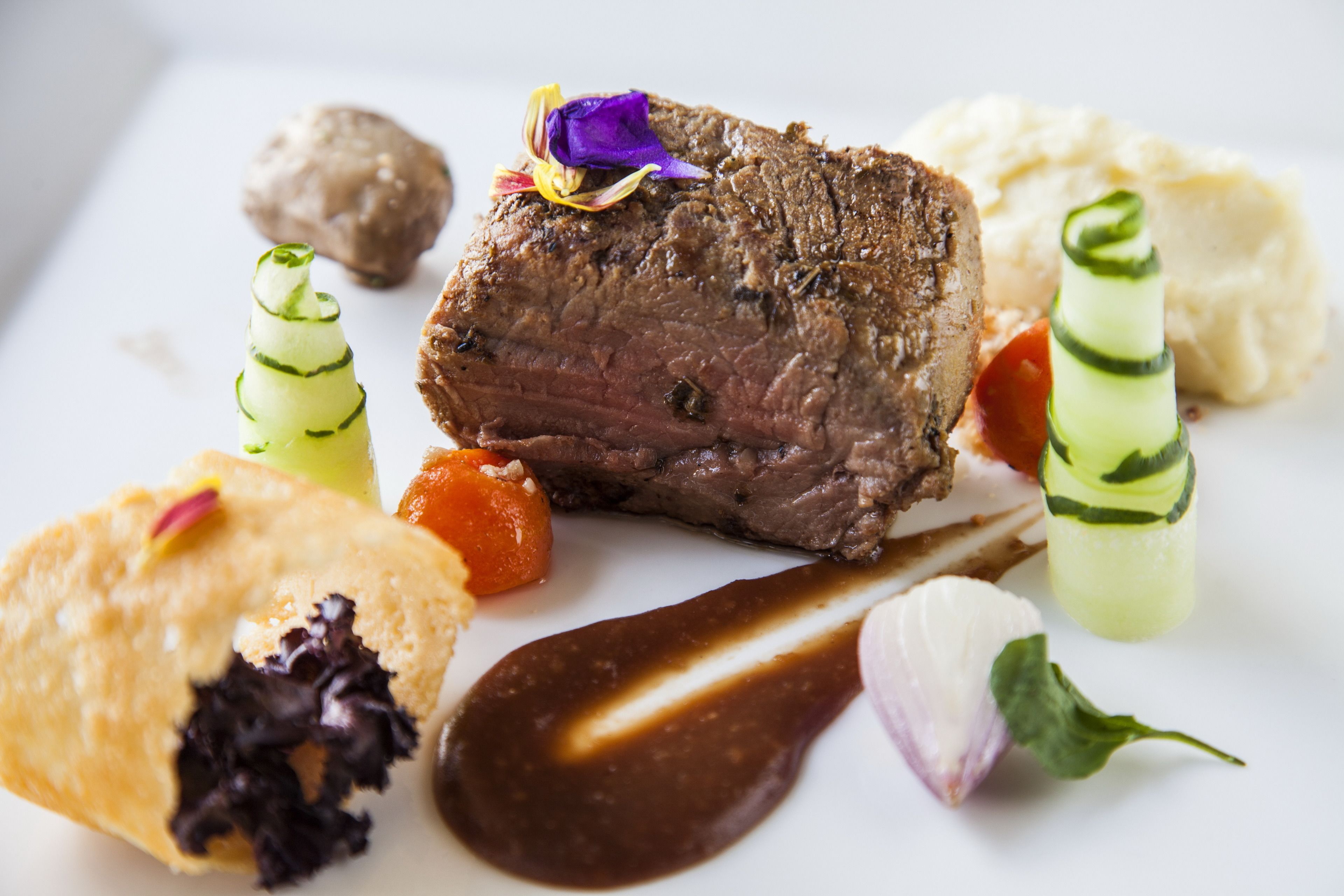 A plated meal with a piece of meat, vegetables, and sauces.