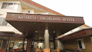 La entrada al Hotel Kusatsu Highland, con un letrero llamativo y un área de recepción cubierta.