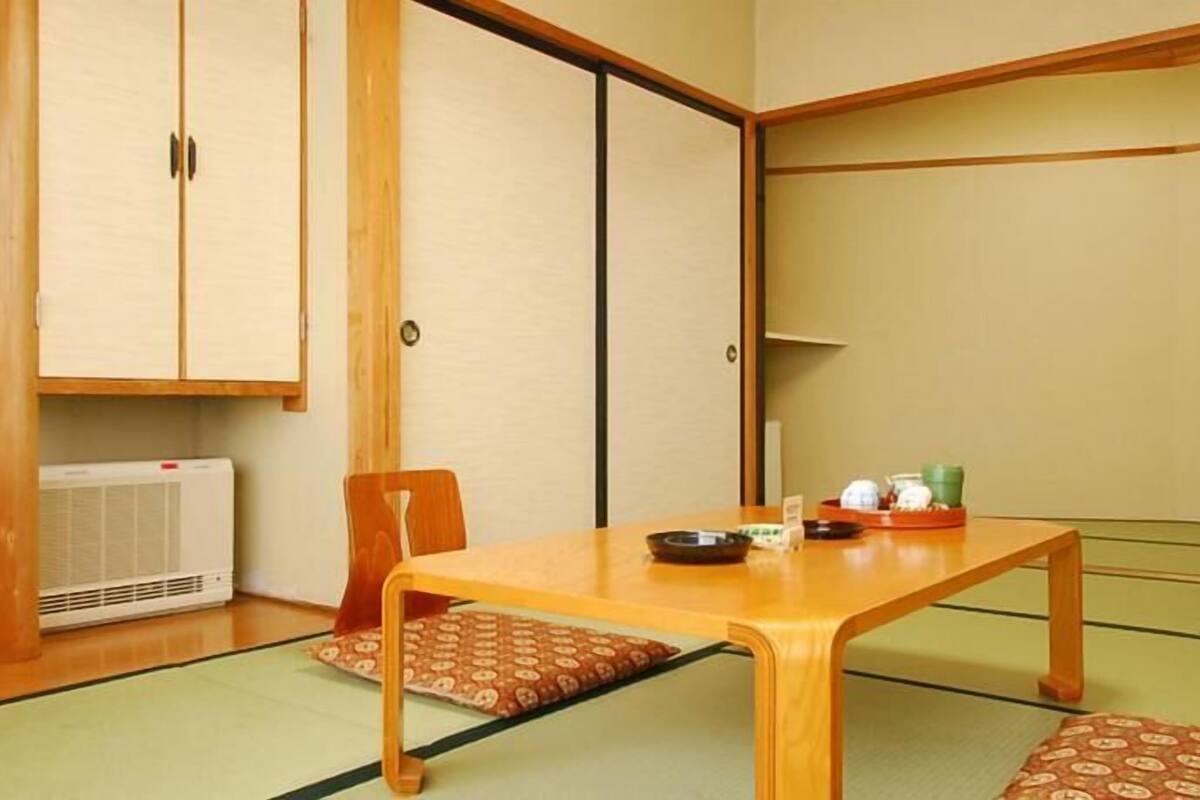 Una habitación japonesa tradicional con suelo de tatami, una mesa de madera baja y un puertas correderas.