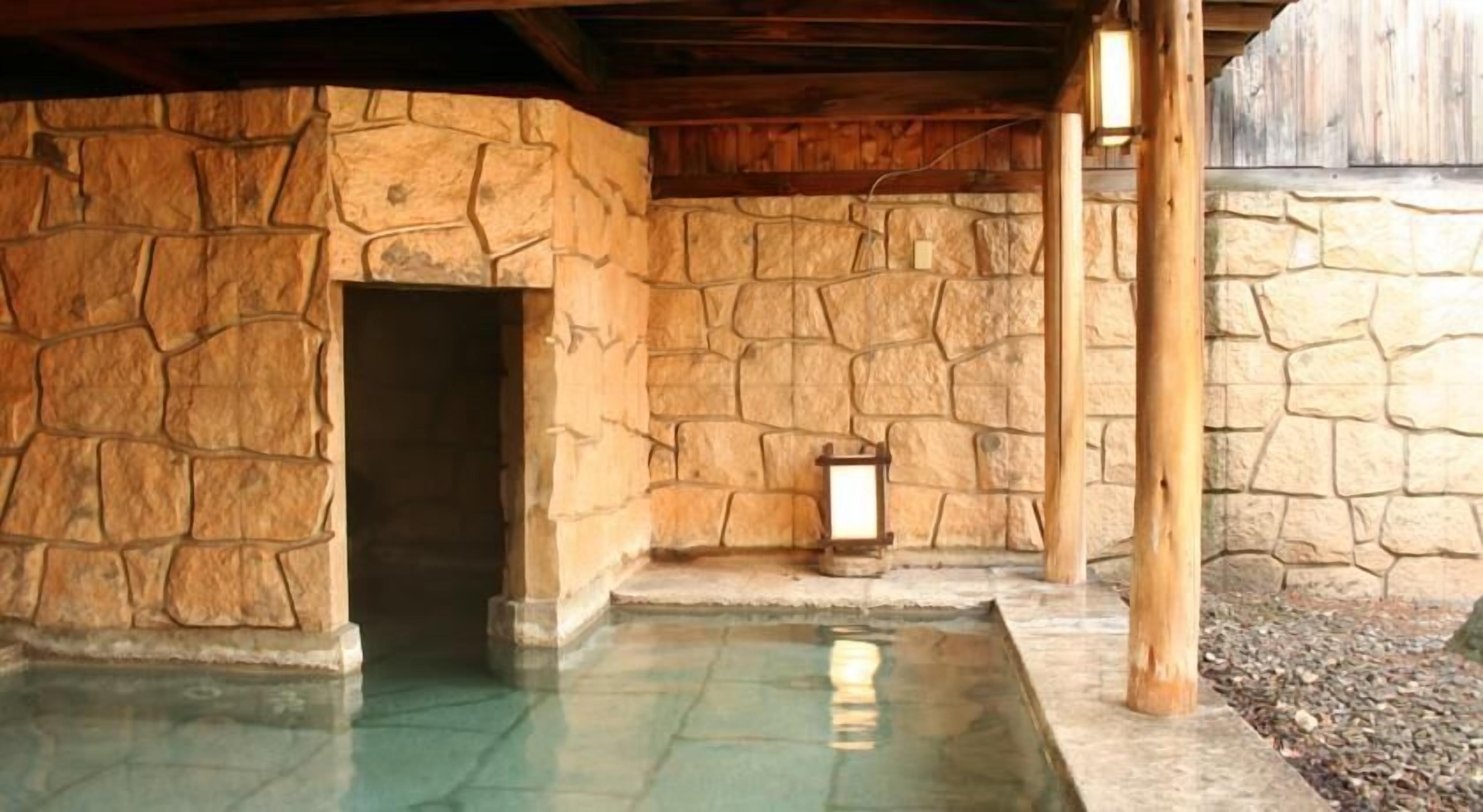 A stone-walled pool area with a door and a lantern.