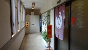 Un pasillo con un reloj, un cartel y una planta en maceta.