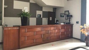 A reception desk with a checkered wall design, a potted plant, and framed certificates. - N Hotel Harmoni Jakarta (Jakarta)