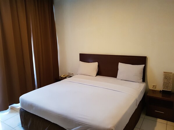 A hotel room with a large bed, a nightstand, a telephone, and a wall-mounted speaker.