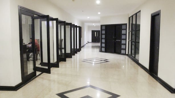 Un couloir doté d’un plancher poli et de portes en verre à cadre noir donnant accès aux pièces.