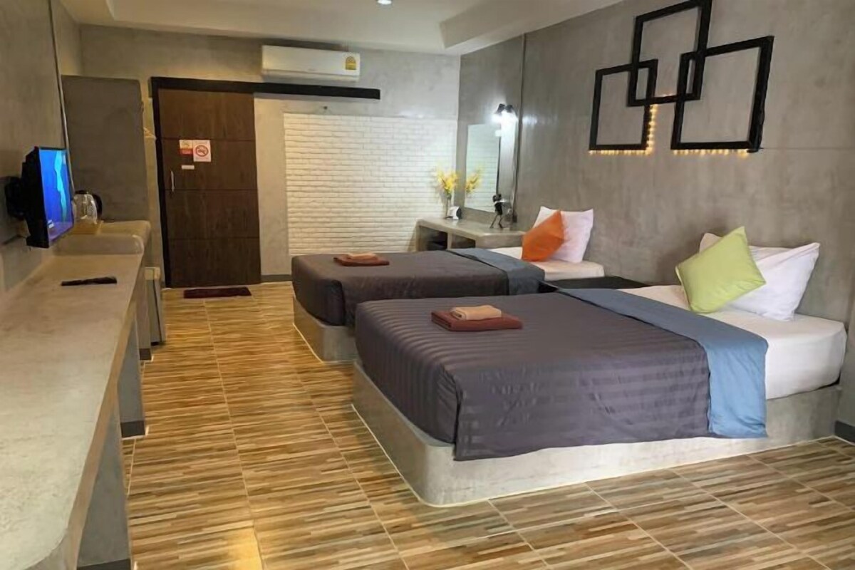A hotel room with two beds, a desk, a mirror, and a TV.