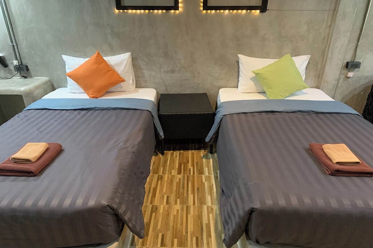 A hotel room with two beds, each with a pillow and a folded towel.
