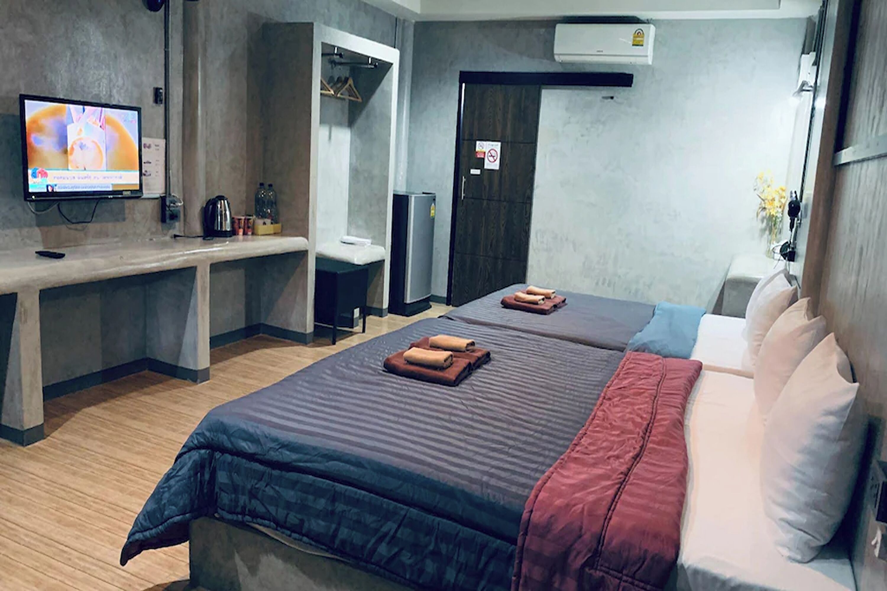 Een hotelkamer met twee bedden, een televisie, een bureau en een kledingkast.