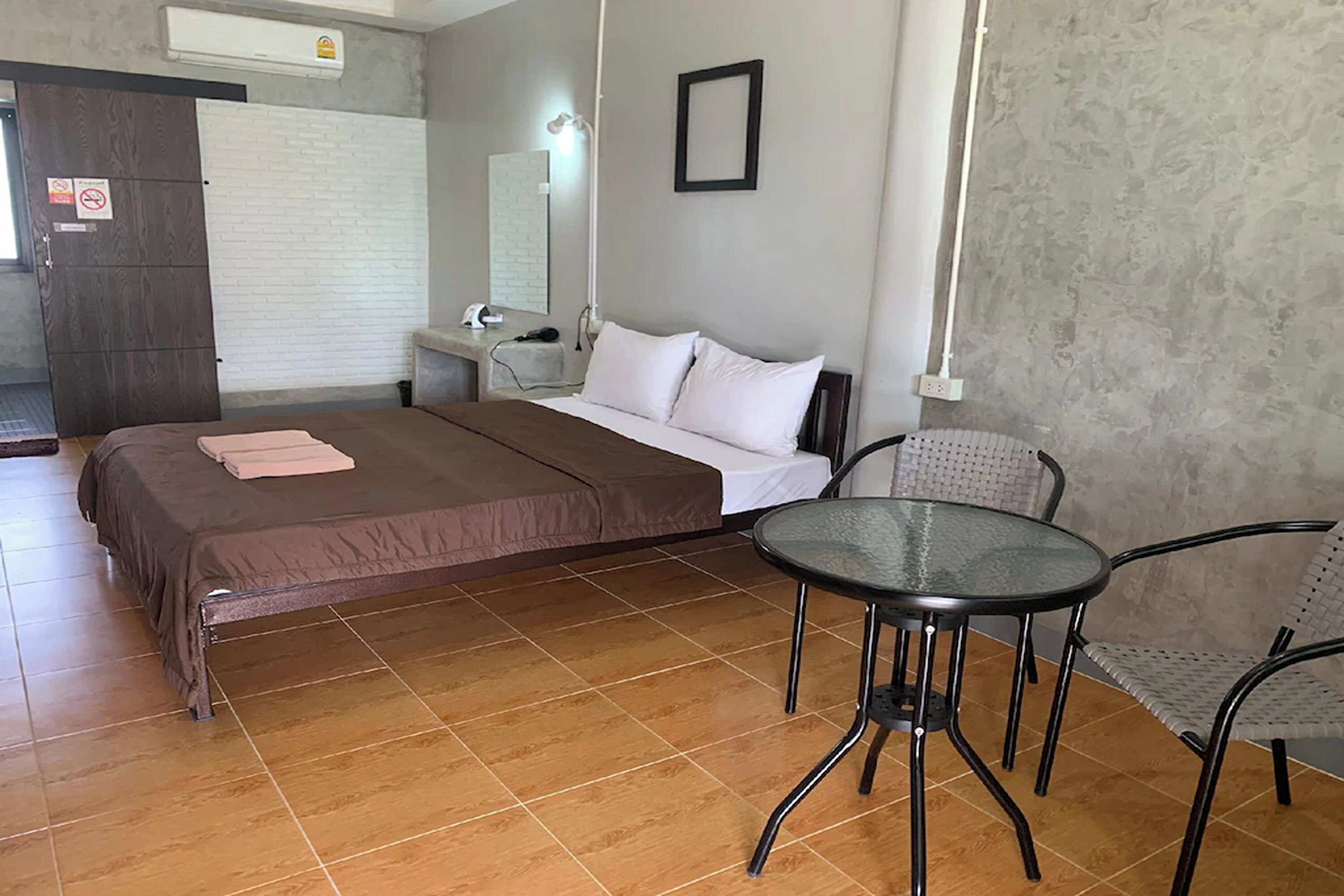 A bedroom with a bed, a desk, a chair, and a small table.