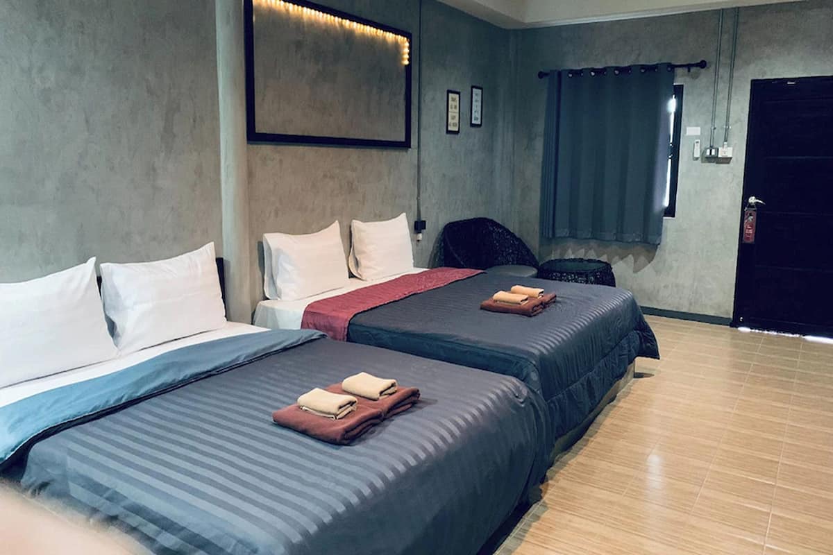 A hotel room with two beds, a large mirror, a chair, and a door.