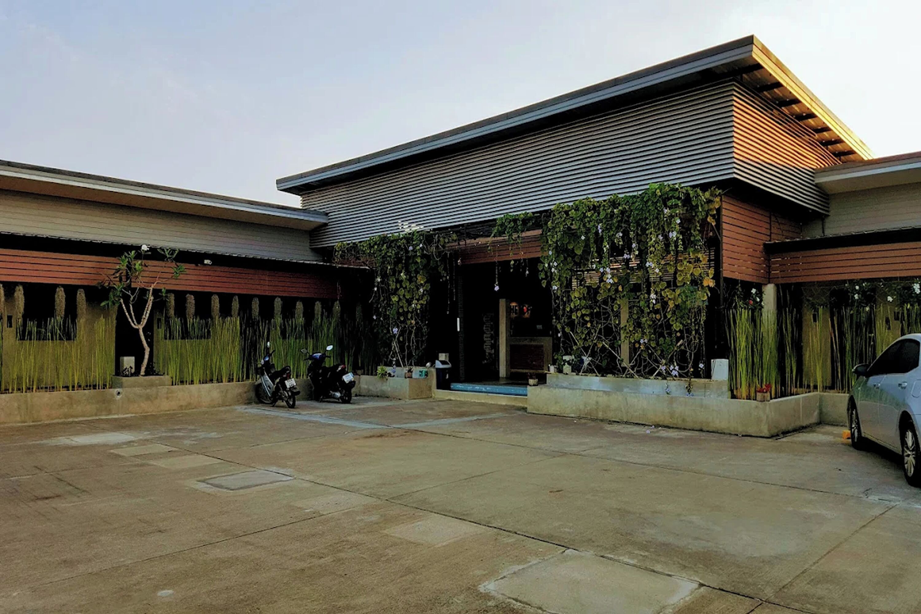 A modern building with a flat roof, large windows, and a paved courtyard.