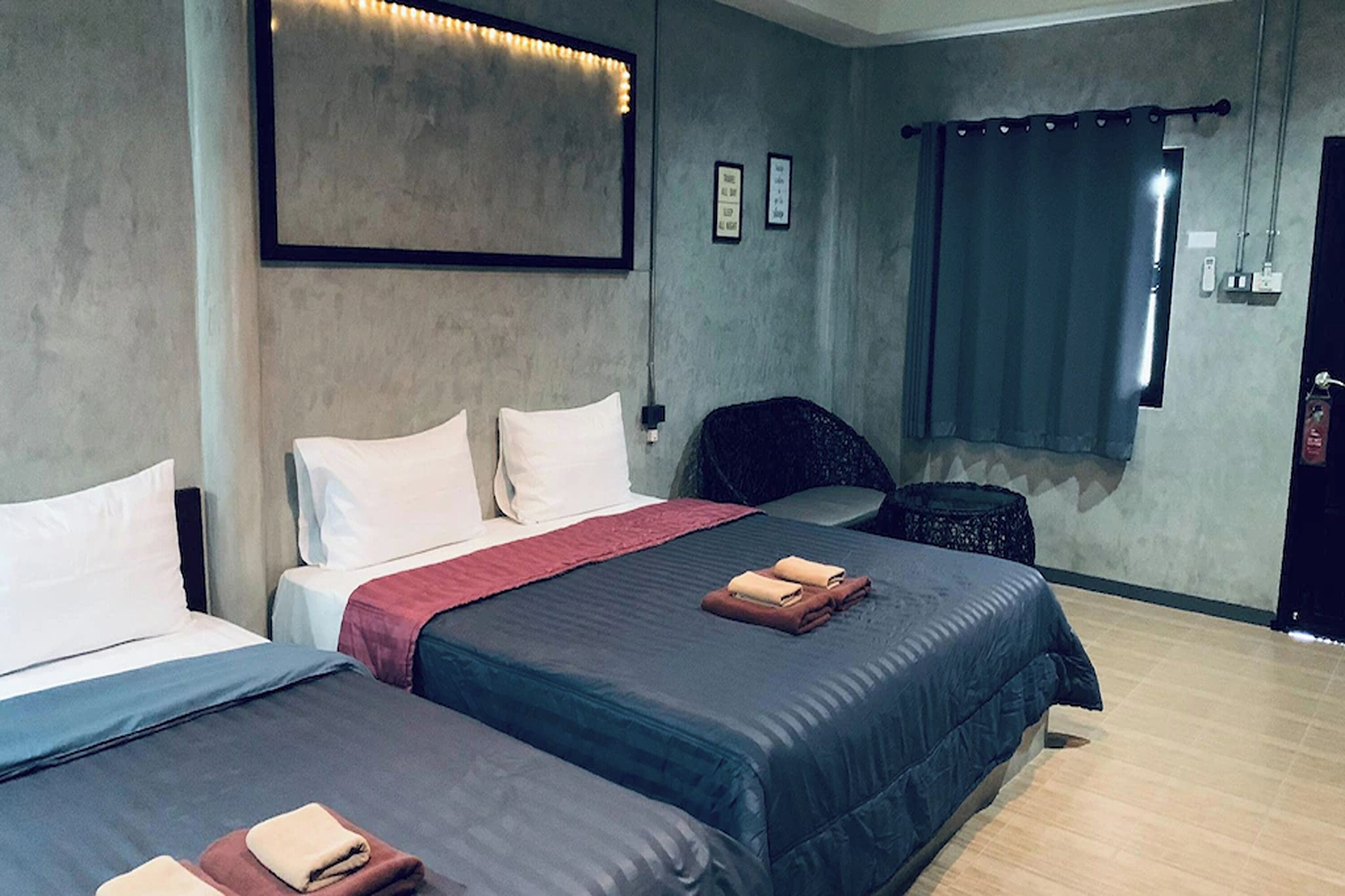 Une chambre d’hôtel avec deux lits, une chaise, une petite table ronde et une fenêtre avec des rideaux.