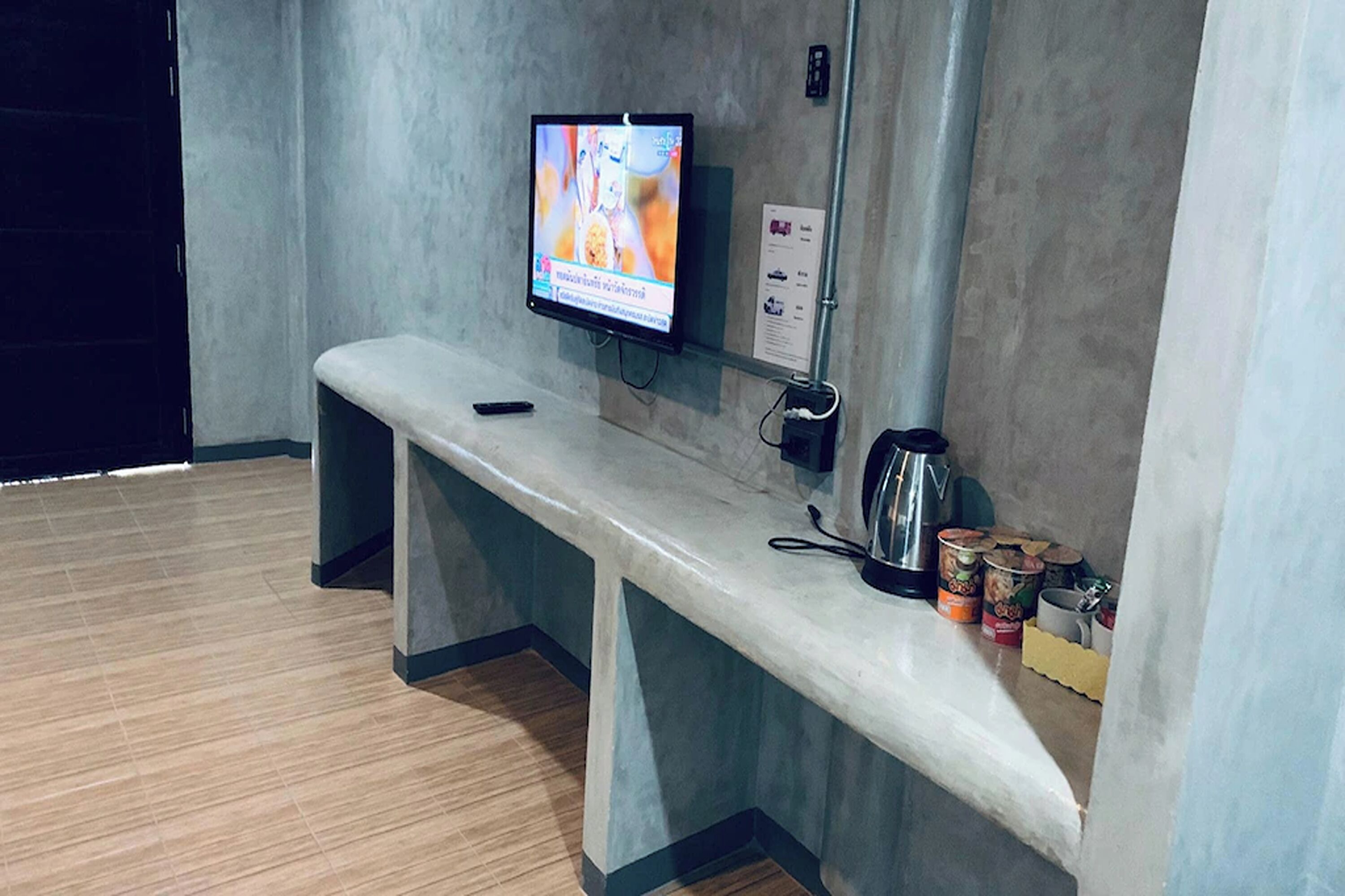 Een bank met een aan de muur bevestigde televisie, een koffiezetapparaat en een paar voedselverpakkingen.