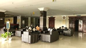 A hotel lobby with leather sofas arranged in a semi-circle, a reception desk, and a staircase leading to the upper floors. - Grand Madani Hotel (Mataram)