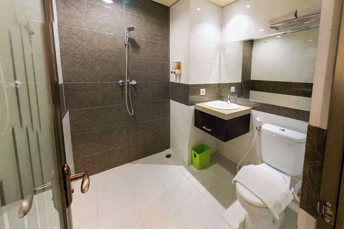 A modern bathroom with a glass shower enclosure, a toilet, and a sink with a mirror above it.