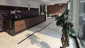 En moderne reception med en trædisk, murstensvæg og glasafskærmning.