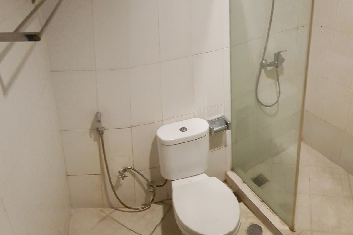 A small bathroom with a toilet, a glass shower enclosure, and a towel rack.