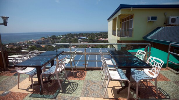 A terrace with a table and chairs, overlooking a coastal view. - C & L Bay View Inn (Dumaguete)