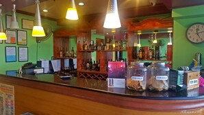 A bar area with a wooden counter, hanging lights, and various bottles and glasses. - C & L Bay View Inn (Dumaguete)