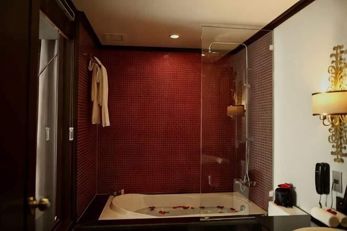 Une salle de bain moderne avec une douche à parois de verre, une baignoire remplie de pétales de roses et une serviette accrochée au mur.