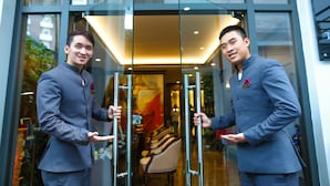 Dos hombres con traje abren una puerta de cristal hacia el vestíbulo de un hotel.