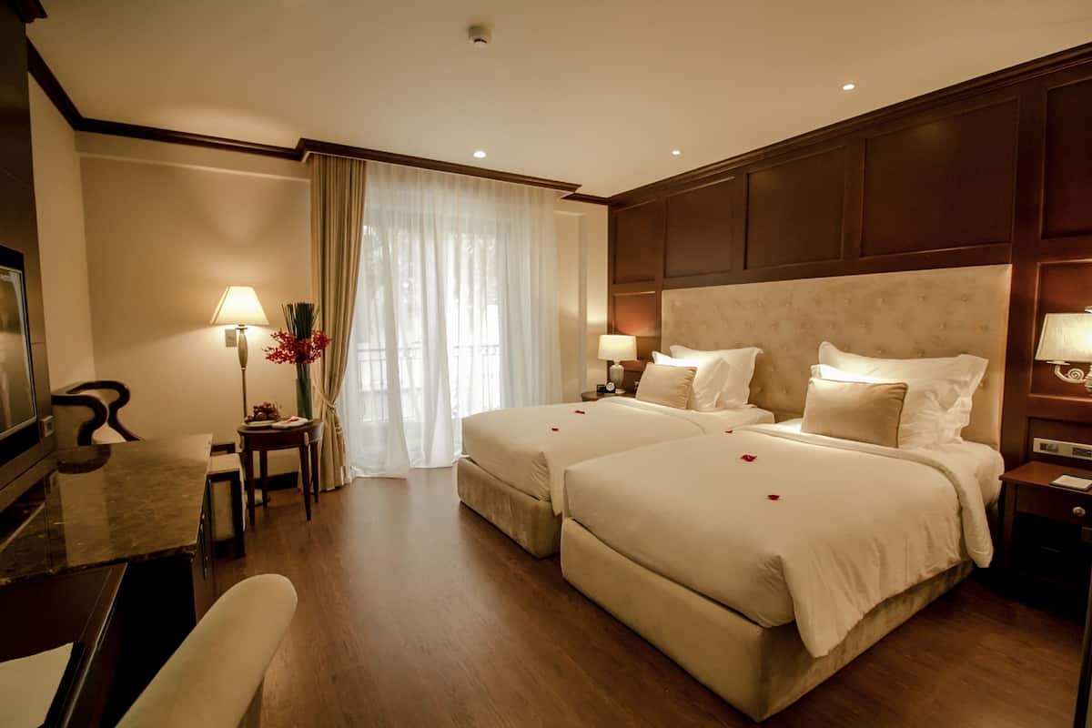 Une chambre d’hôtel avec deux lits, un bureau, une chaise et une télévision.