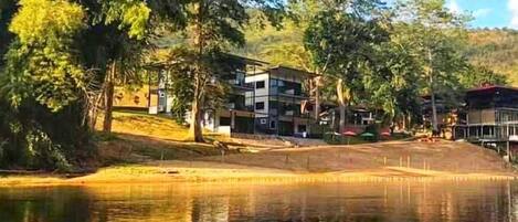 A lakeside property with modern buildings, a dock, and surrounding trees.