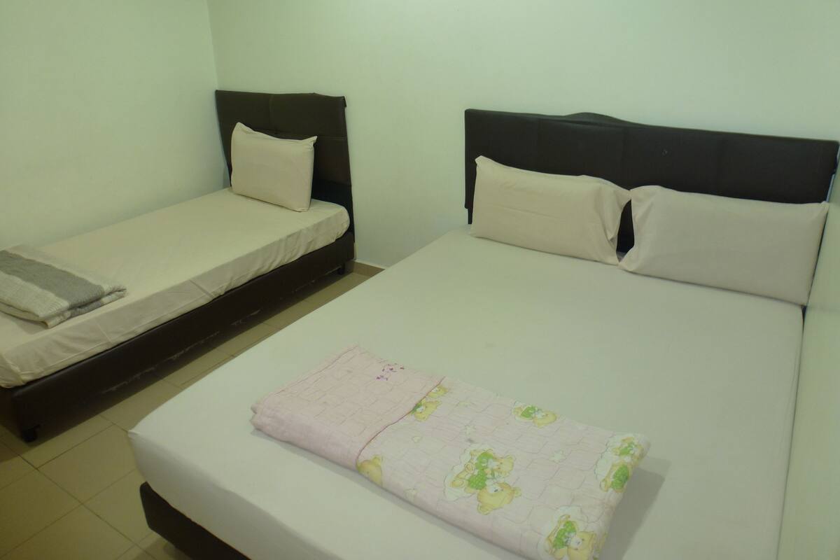 Une chambre d’hôtel avec deux lits simples et un lit double.