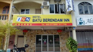 Un hôtel appelé Batu Berendam Inn, avec une enseigne indiquant son nom et ses numéros de téléphone.