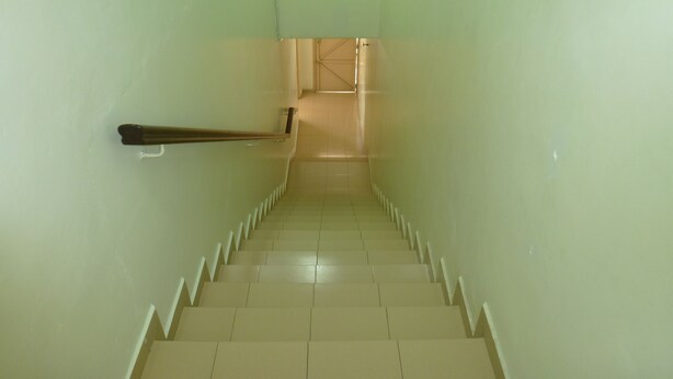 Un escalier muni d’une rampe, menant à une porte située en haut.